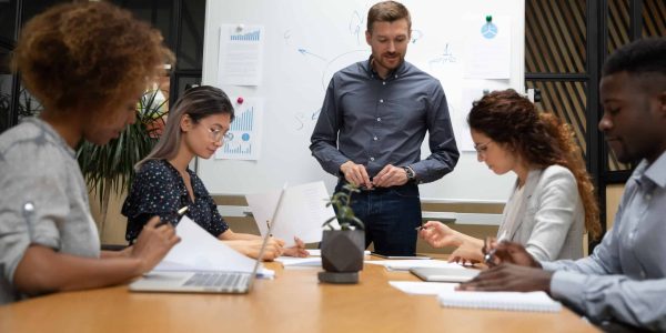 Multiethnic staff take part in a website SEO audit led by manager in a boardroom.