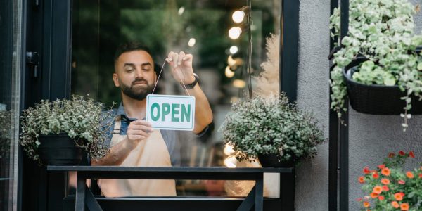 Male business owner preparing storefront for customers after using a local SEO checklist.
