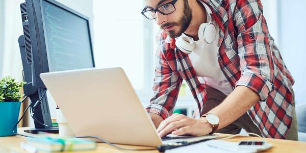 Young software developer standing at his desk and working on a technical SEO checklist.